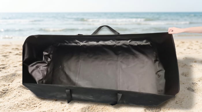 Aerowave inflatable boat bag open on the sand during pack-down at the beach