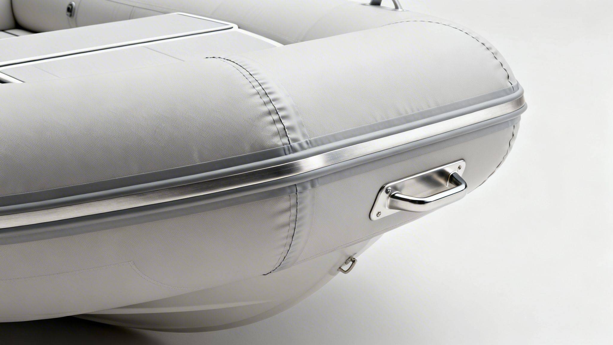 Close-up of a light gray inflatable boat featuring a polished metal handle and side rub rail.