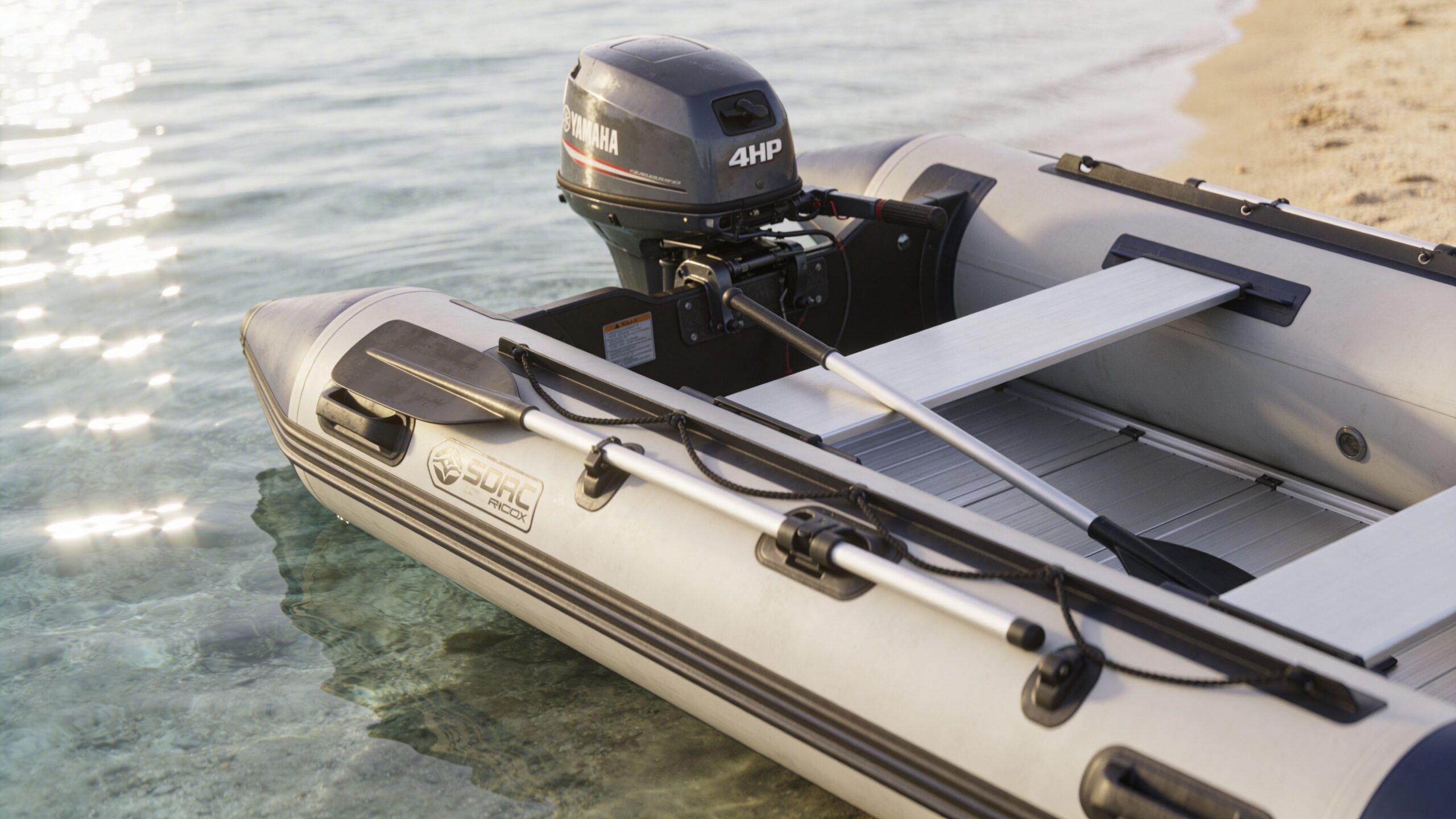 A gray inflatable boat with a 4 horsepower Yamaha outboard motor sits in shallow coastal water.