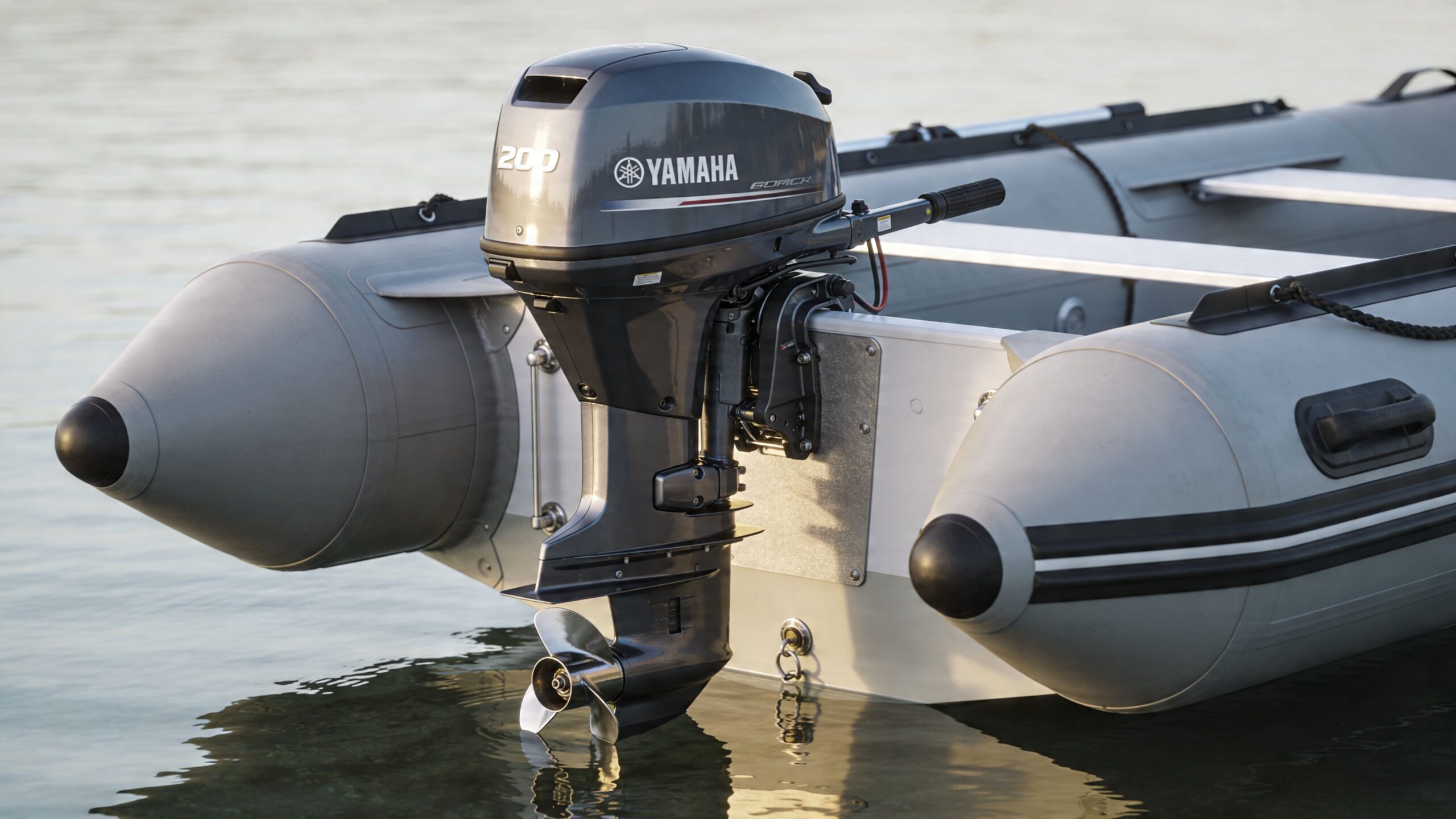 A gray Yamaha outboard motor mounted on the back of a stable inflatable boat in calm water.